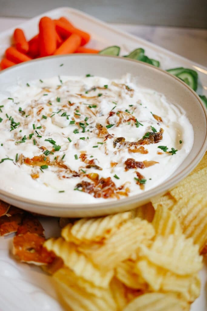 sour cream and onion dip  with chips carrots cucumber pretzels 