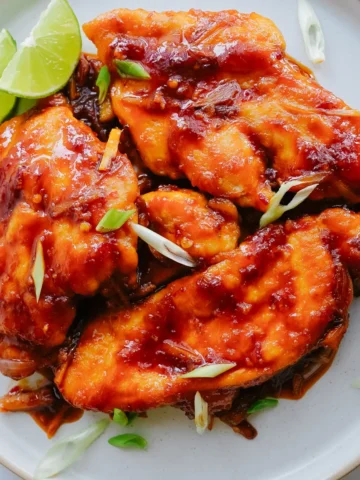 Delicious Honey Sriracha Chicken Recipe plated with lime and green onion garnish
