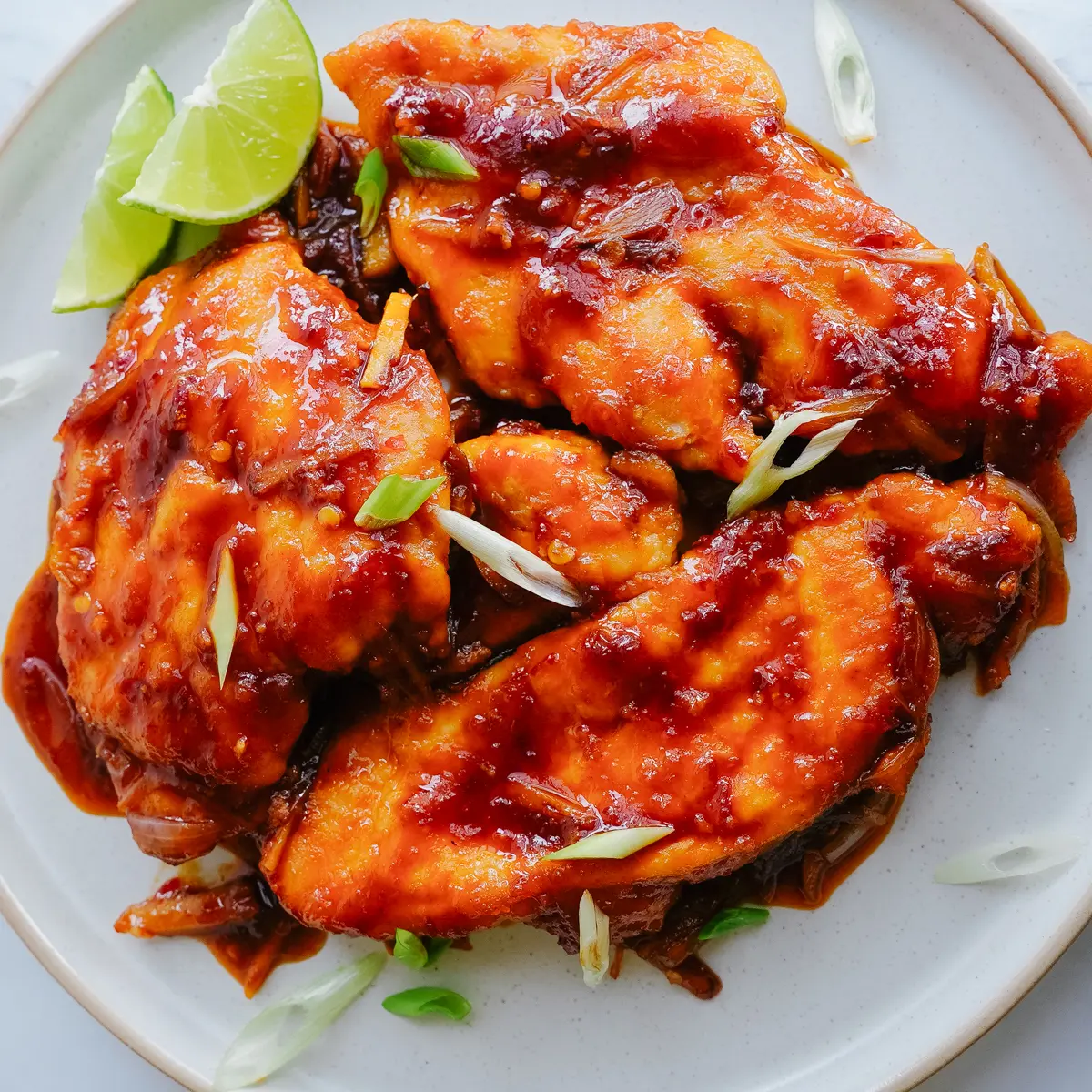 Delicious Honey Sriracha Chicken Recipe plated with lime and green onion garnish